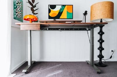 a desk with a lamp and a painting on the wall