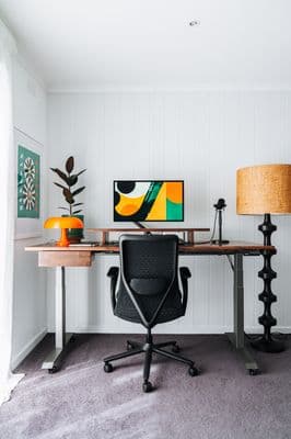 a desk with a chair and a lamp in a room