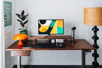 a desk with a computer and a lamp on it