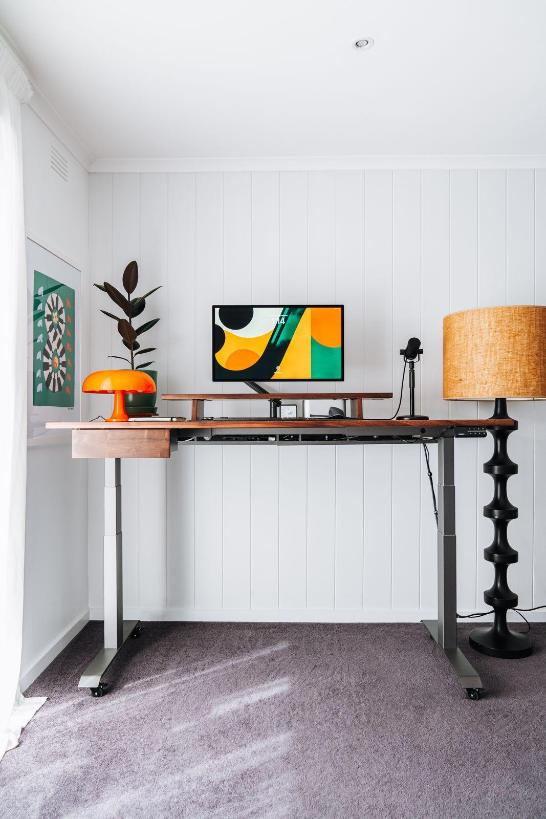 a desk with a lamp and a painting on the wall