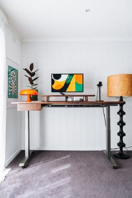 a desk with a lamp and a painting on the wall