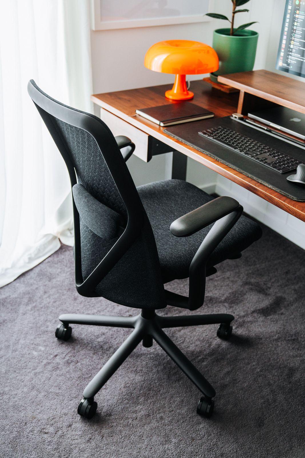 a black office chair sitting in front of a computer desk