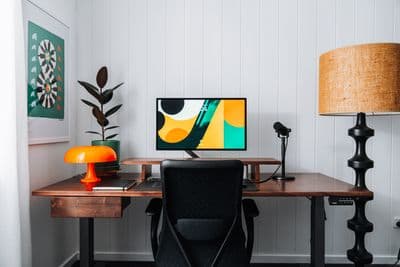 a desk with a computer and a lamp on it