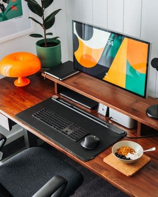 a desk with a computer and a bowl of cereal