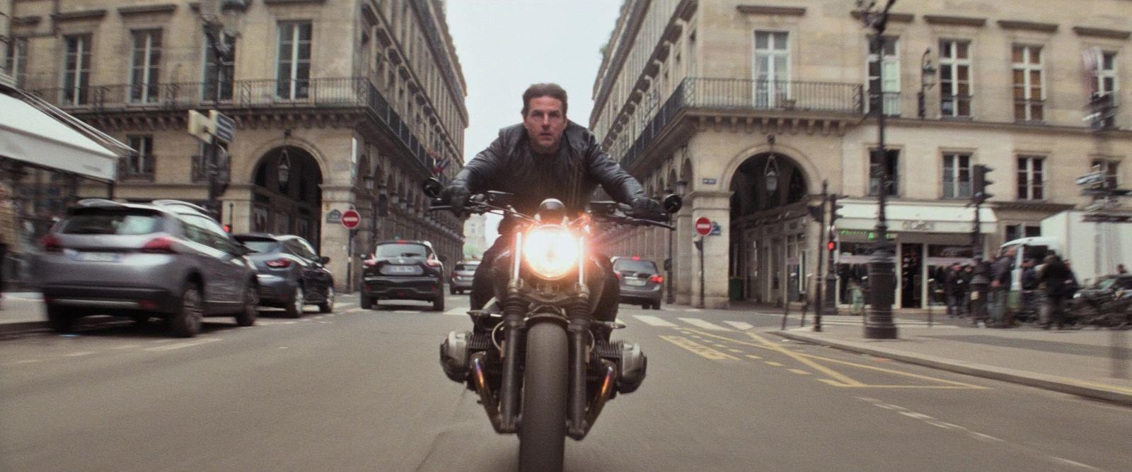 a man riding a motorcycle down a city street