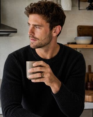 a man in a black sweater holding a coffee cup