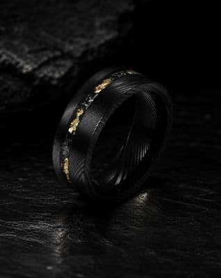 a black and gold wedding ring on a black surface