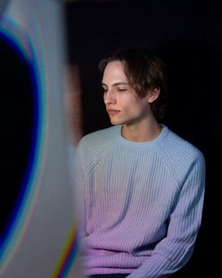 a man in a blue sweater looking at a laptop