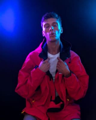 a man in a red jacket sitting on a stool