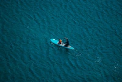 two people in a small boat in the middle of the ocean