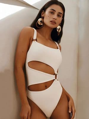 a woman in a white bodysuit leaning against a wall
