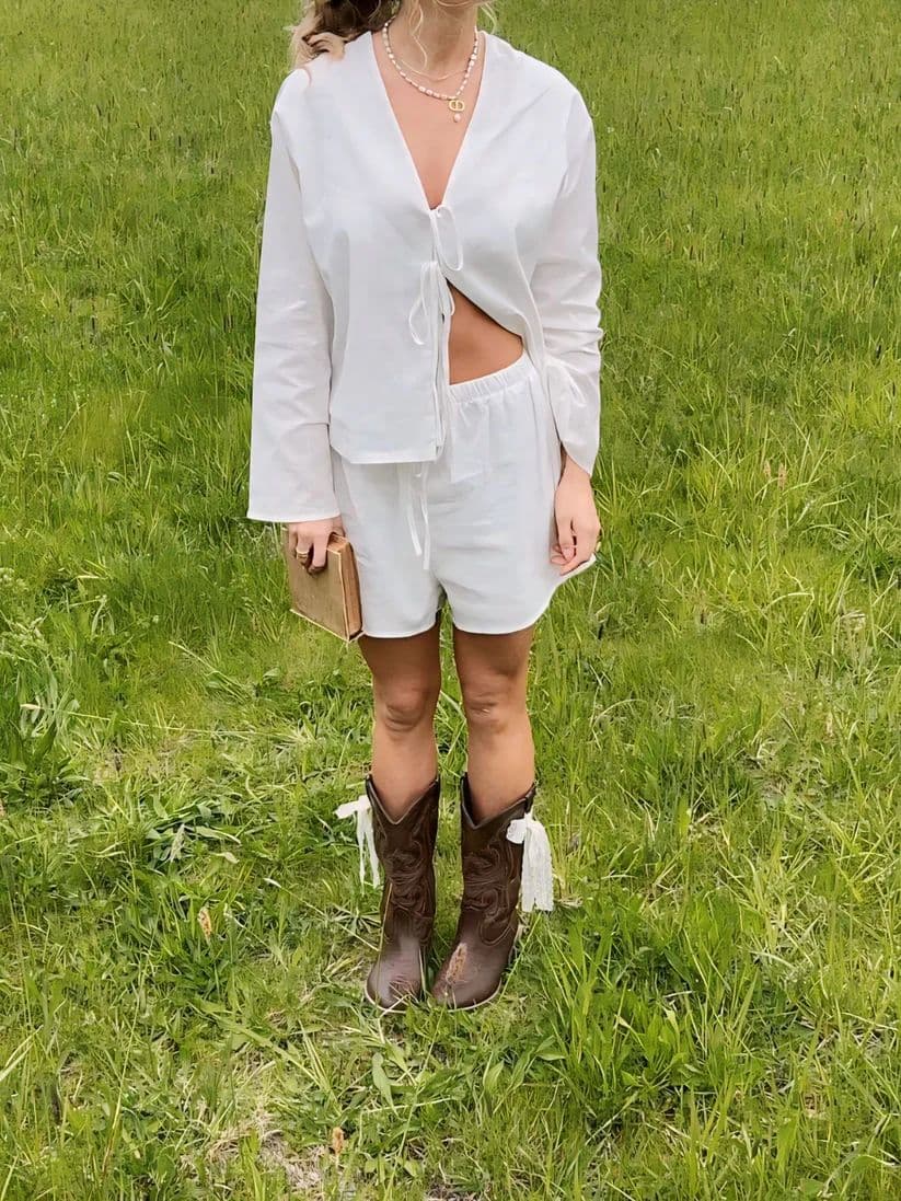a woman standing in a field wearing a white outfit