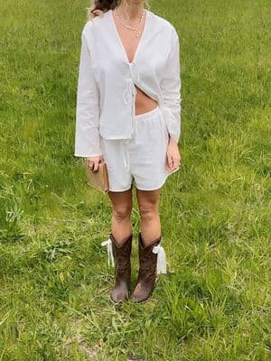 a woman standing in a field wearing a white outfit