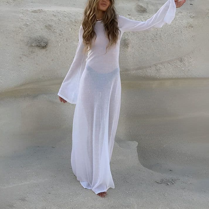 a woman in a white dress standing in the sand