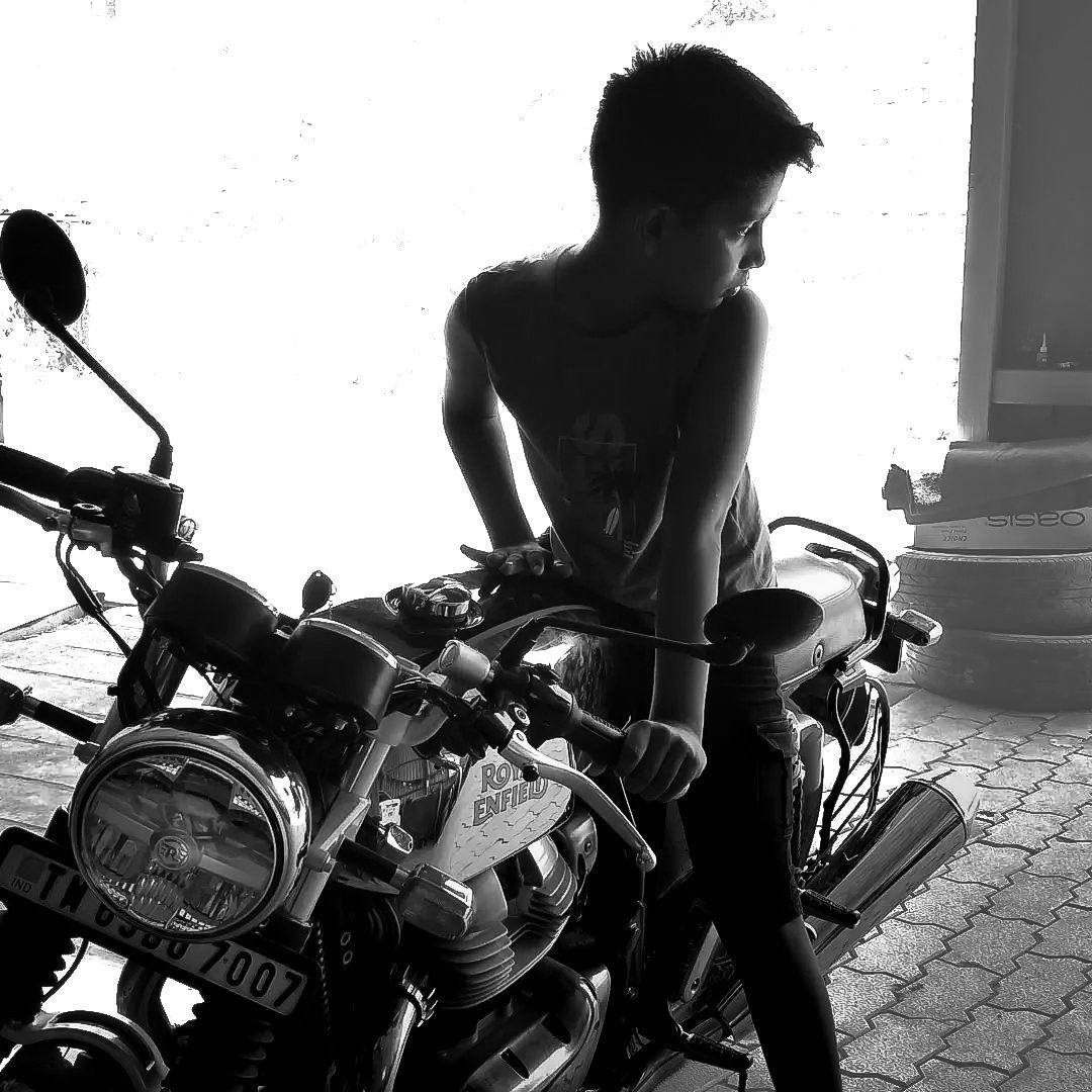 a young boy standing next to a parked motorcycle