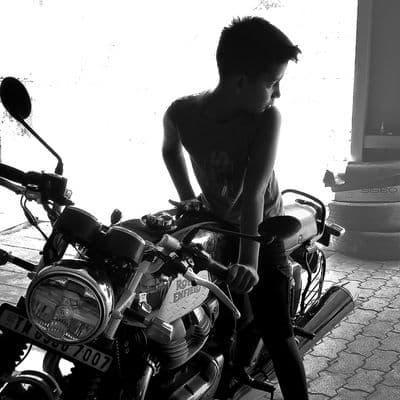 a young boy standing next to a parked motorcycle