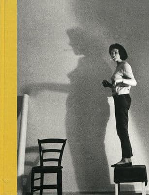 a black and white photo of a woman standing on a chair