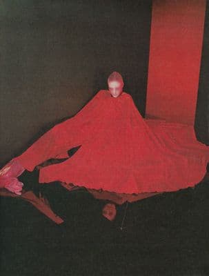 a woman in a red dress sitting on a black floor