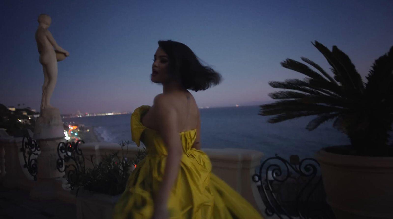 a woman in a yellow dress standing next to a statue