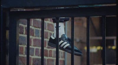 a pair of black and white shoes hanging on a fence