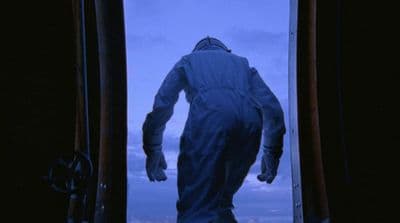 a man in a white suit standing in a doorway