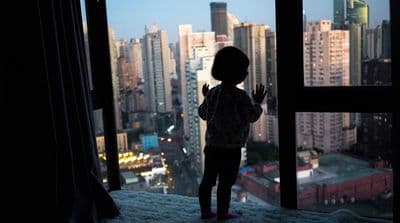 a little girl standing in front of a window
