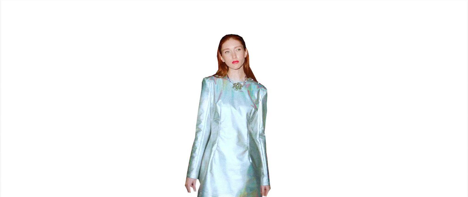 a woman in a blue dress standing in front of a white background