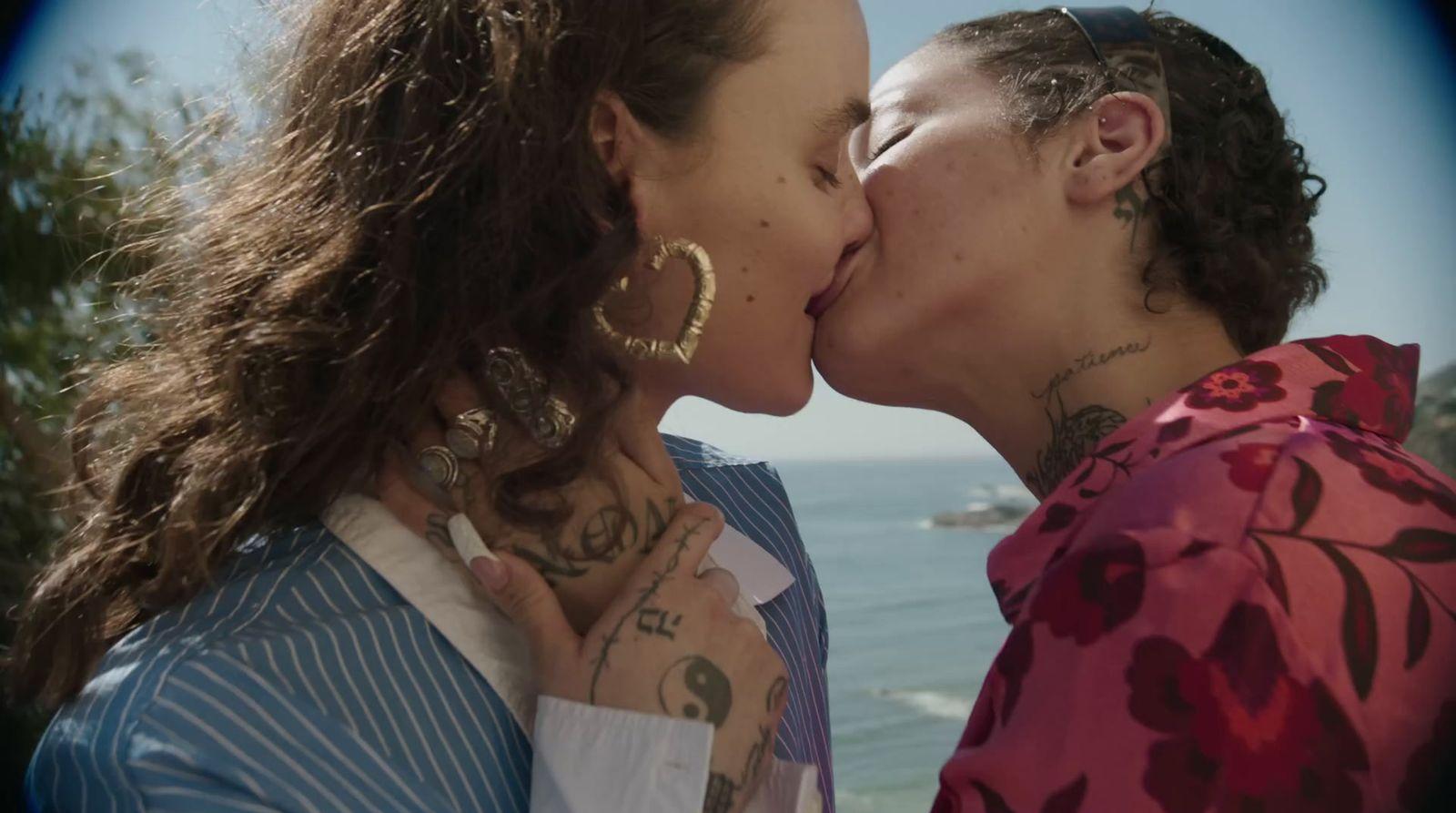 a couple of women kissing each other near the ocean