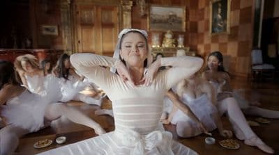a group of women in white dresses sitting on the floor