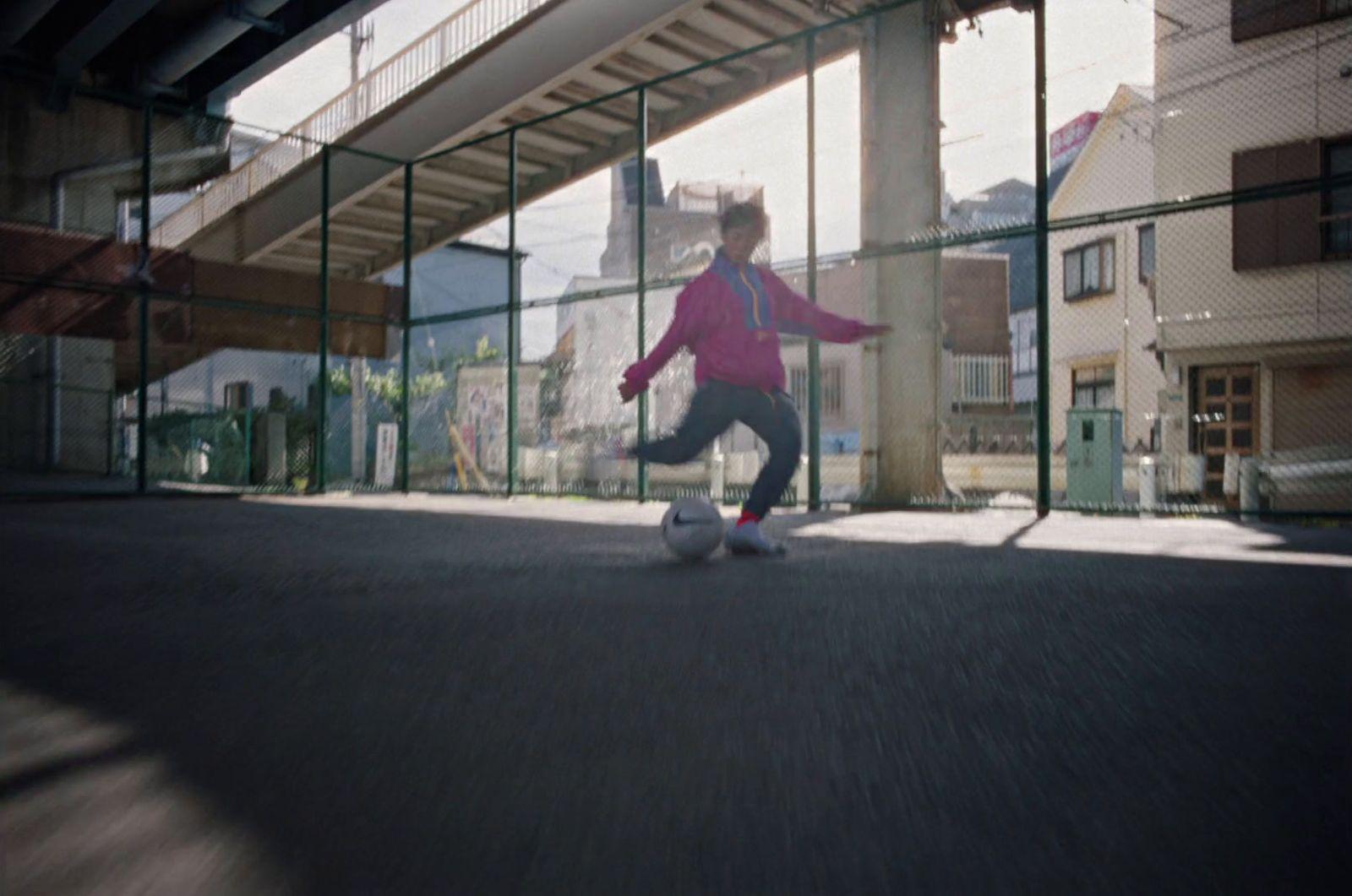 a young girl kicking a soccer ball under a bridge