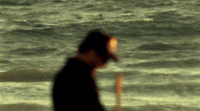 a man standing on top of a beach next to the ocean