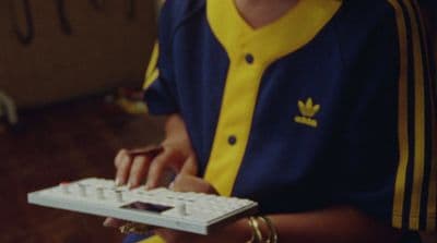 a person holding a computer keyboard and wearing a yellow and blue shirt