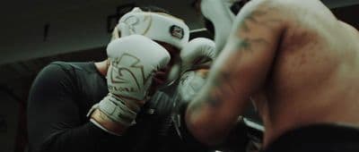 a man with a tattoo on his arm wearing boxing gloves