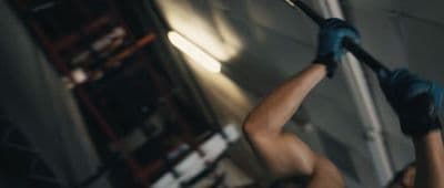a woman in blue gloves holding a baseball bat