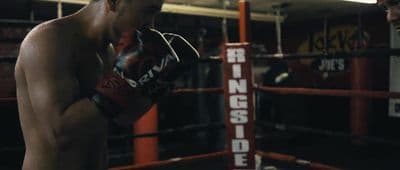 a shirtless man standing next to a boxing ring
