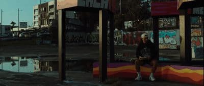 a person sitting on a bench in front of a puddle