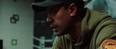 a man wearing a green hoodie and a black hat