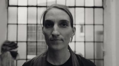 a black and white photo of a woman in front of a window