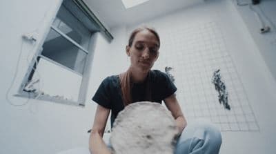 a woman sitting on a toilet holding a ball of yarn