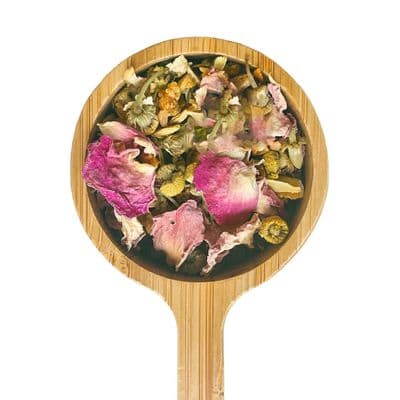 a wooden spoon filled with dried flowers on top of a white background