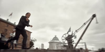 a man in a suit is walking on a bridge