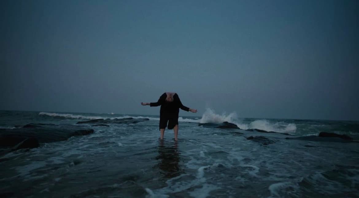 a woman standing in the ocean with her arms outstretched