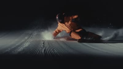 a snowboarder sliding down a snow covered slope