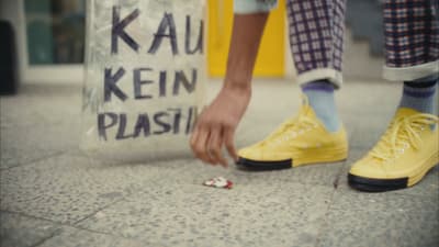 a person with yellow shoes is picking up a plastic bag