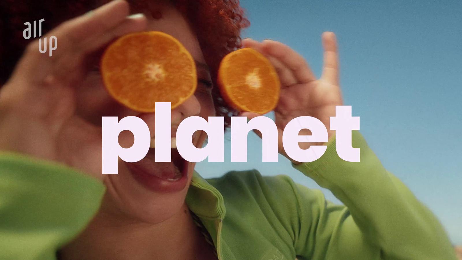 a woman holding up two orange slices to her face