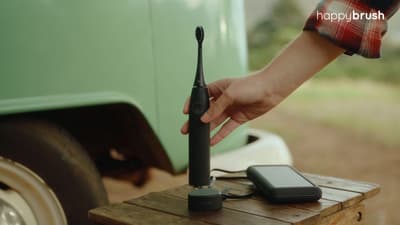 a person holding a cell phone near a green truck