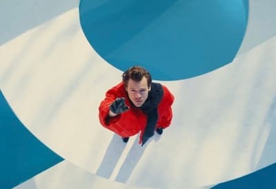 a man in a red jacket standing in front of a blue and white wall