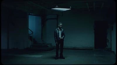 a man standing in a dark room with his hands in his pockets