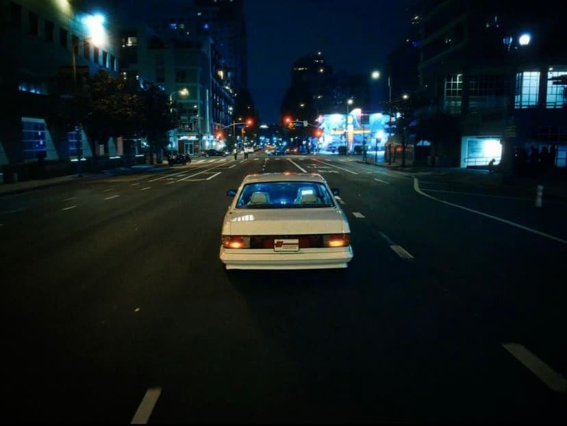 a white car driving down a city street at night