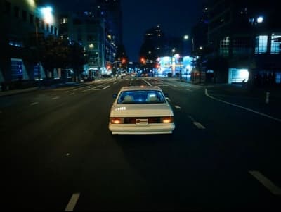 a white car driving down a city street at night